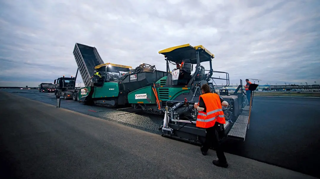 Worker making asphalt with paving machine