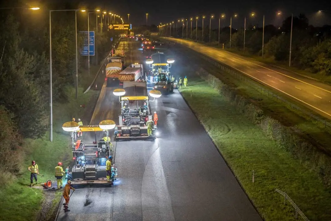 pavement workers working at night on a sideway road